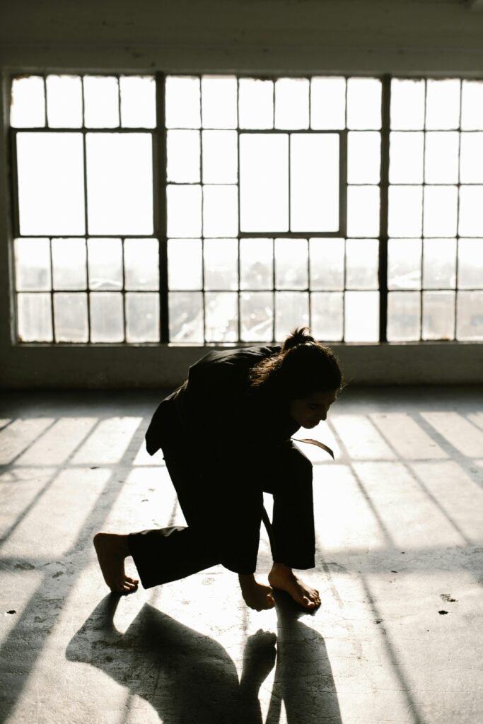 Woman in Black Long Sleeve Shirt and Black Pants Sitting on Concrete Floor
